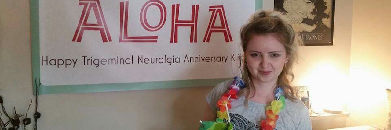 How I've Made My Trigeminal Neuralgia Less Scary and More Manageable A picture of the writer in front of a banner that was made for one of her anniversary parties.