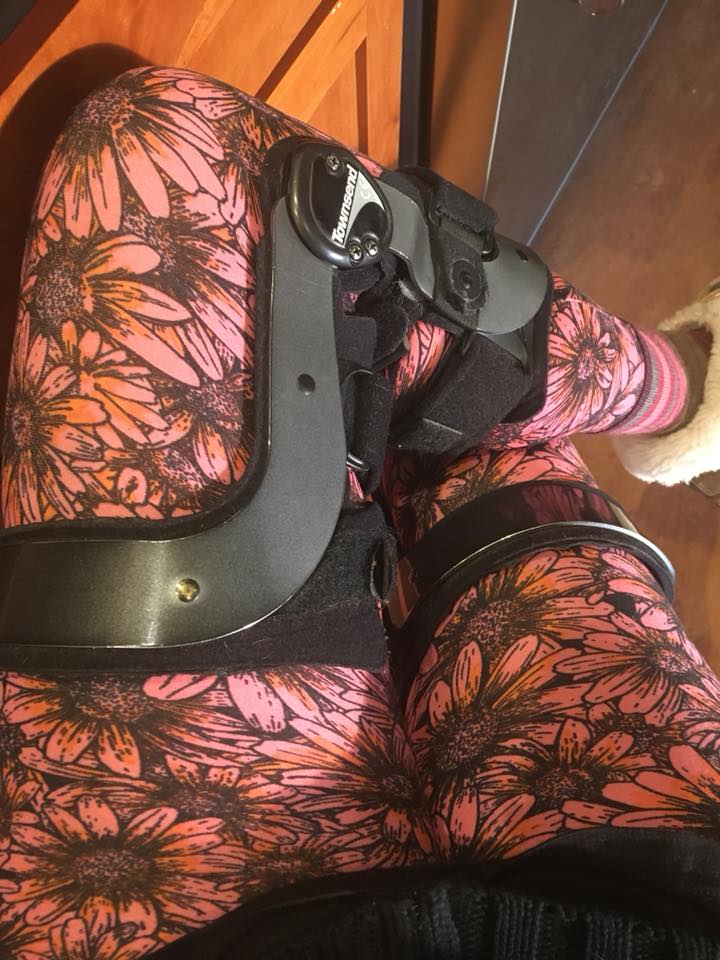 woman wearing pink floral leggings and a knee brace
