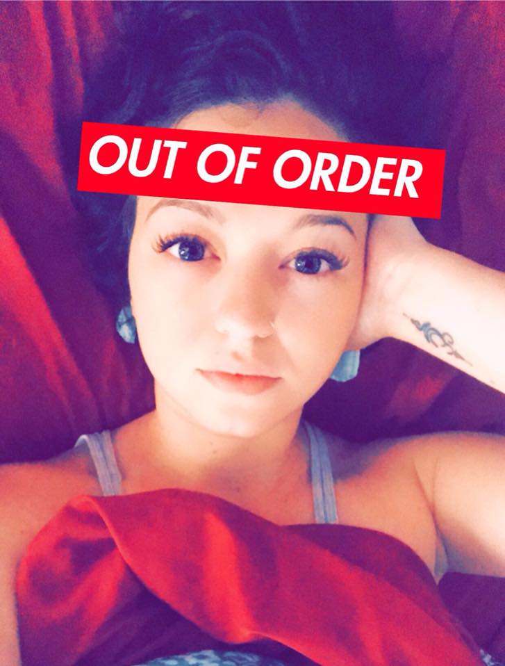 woman lying in bed with an 'out of order' sign across her forehead