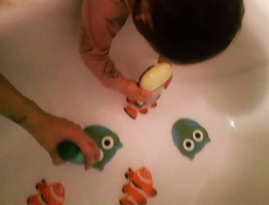 woman and her daughter using shampoo bottles to push down nonslip stickers onto the bottom of the bathtub