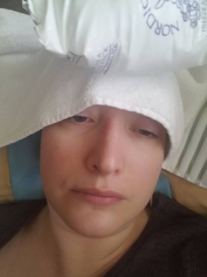 woman lying down with an ice pack on her head and a heating pad under her neck