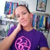 the author wearing her purple 26.2 shirt and standing in front of a wall of medals