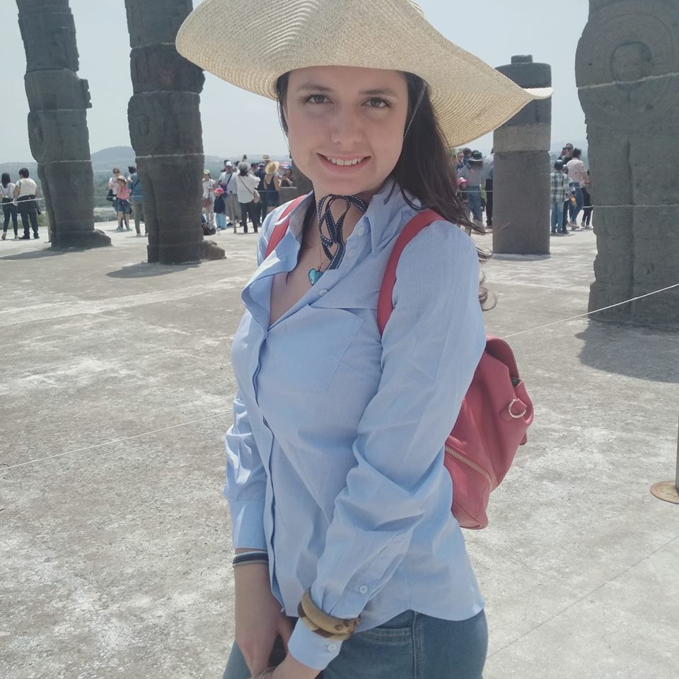 woman standing outside wearing a long sleeve blue shirt and a wide-brimmed hat