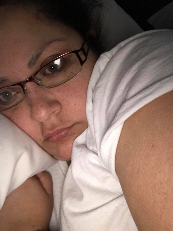 woman lying in bed wearing glasses