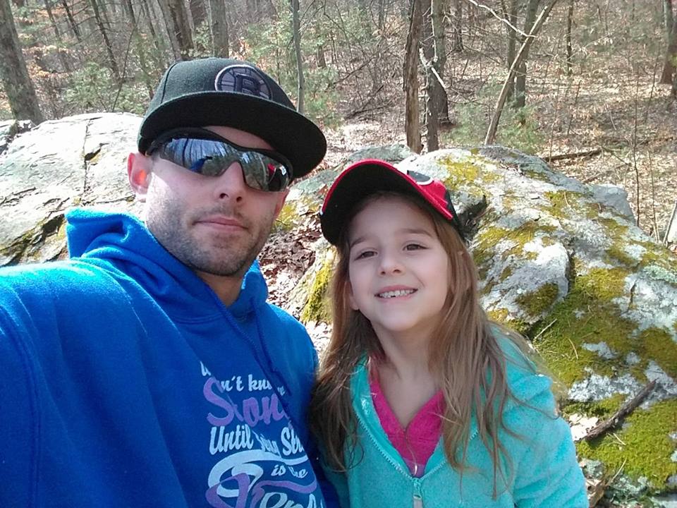 man smiling with his daughter while out in the woods on a hike