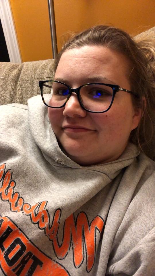 woman wearing a gray sweatshirt and glasses taking a selfie
