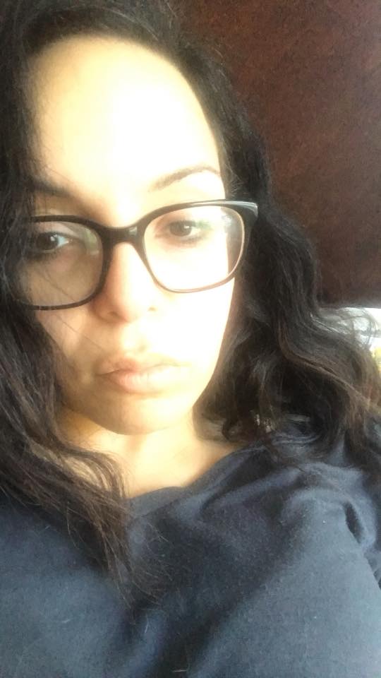 woman lying in bed wearing glasses and frowning