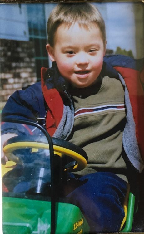 Boy with Down syndrome riding a toy tractor