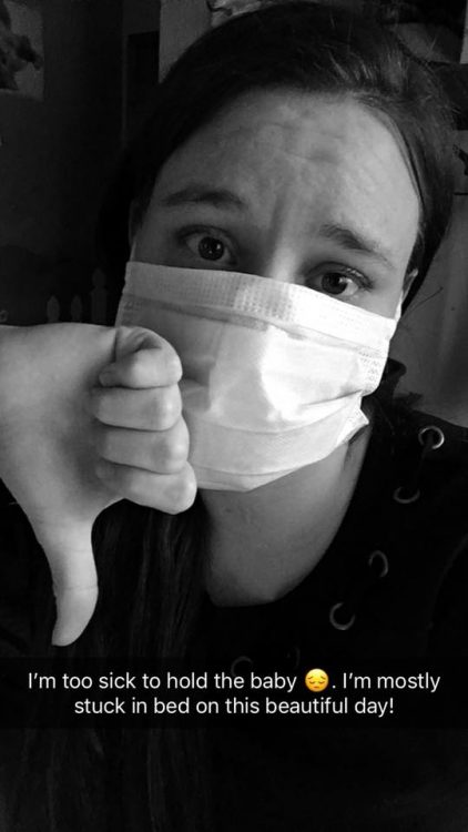 girl wearing surgical mask giving thumbs down