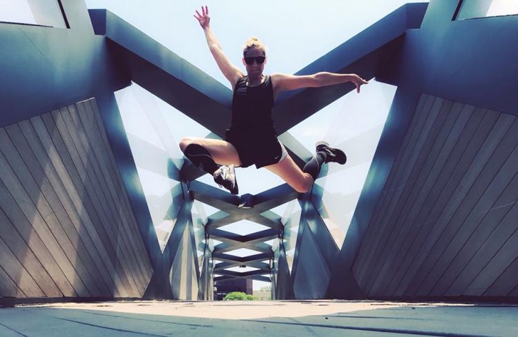 woman jumping in the air under sculpture