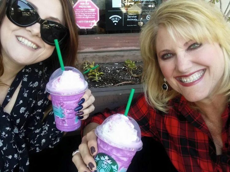 two women smiling holding starbucks drinks