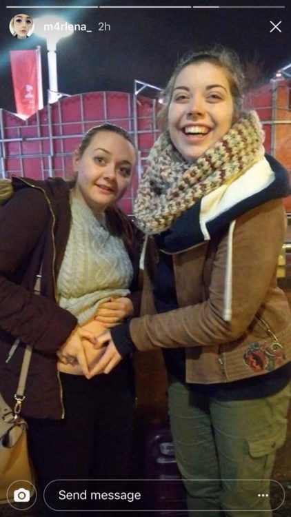 two women with fingers forming a heart on one's stomach