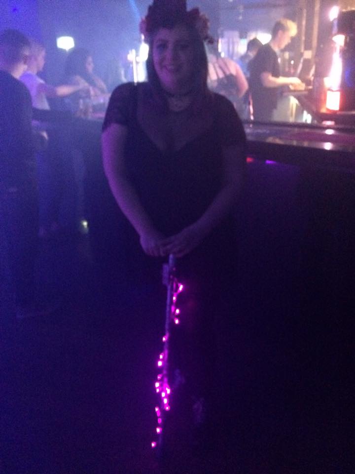 woman at a party with a walking stick covered in lights