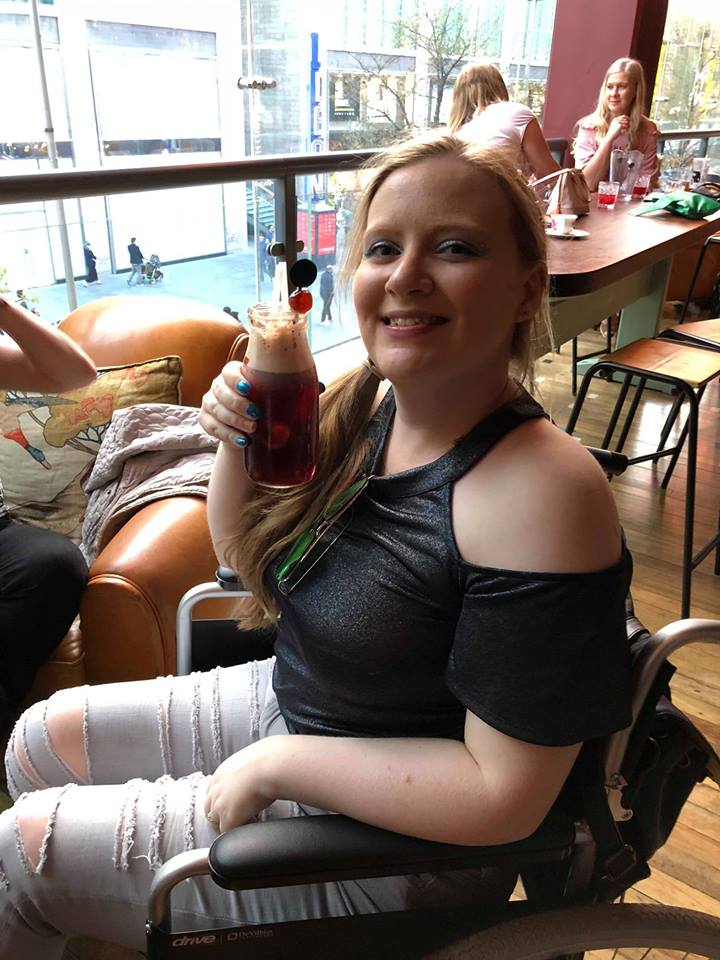 woman sitting in her wheelchair and drinking a fruity cocktail