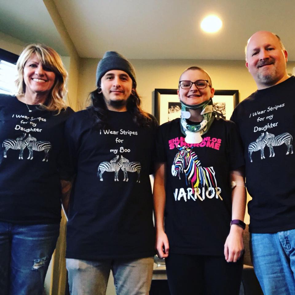 woman wearing a neck brace standing with her boyfriend and parents. they're all wearing matching shirts to support her