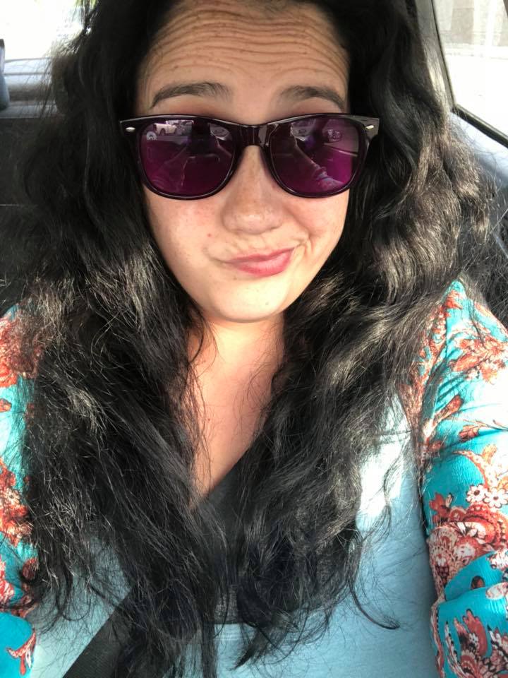 woman taking a selfie in the car. she's wearing a blue shirt and sunglasses