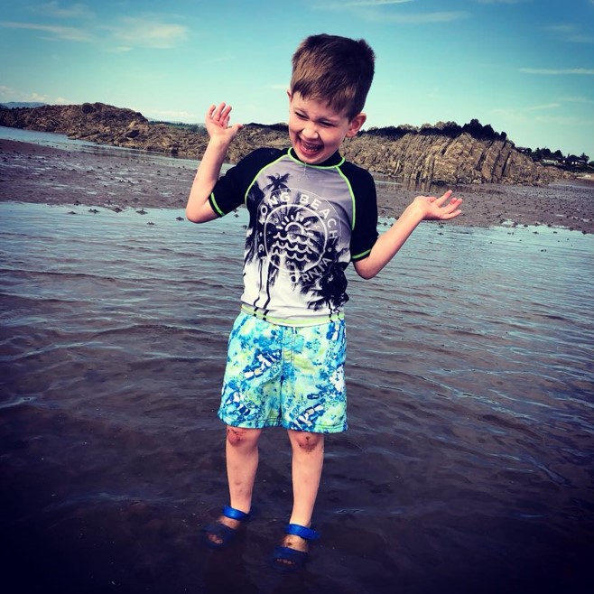 Little boy with disability full of joy standing in the middle of a lake