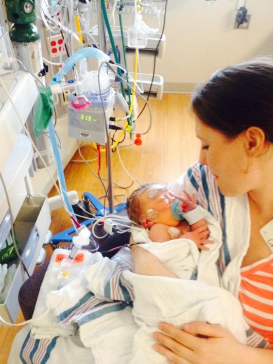 Mother holding baby in NICU, baby has many wires