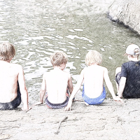 Boys sitting by a lake.