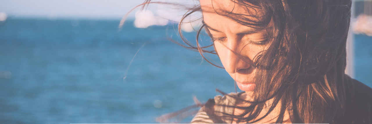 What People Want to Say to the Friends They Lost Because of Depression young woman by sea with wind in hair looking down