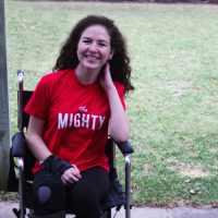 a photo of the author in a wheelchair wearing a shirt that says "The Mighty"