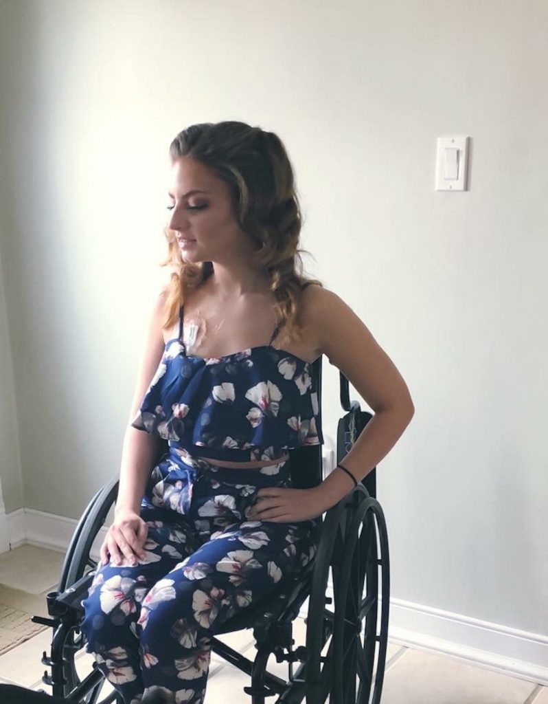 woman wearing a blue dress and sitting in a wheelchair with her hand on her hip