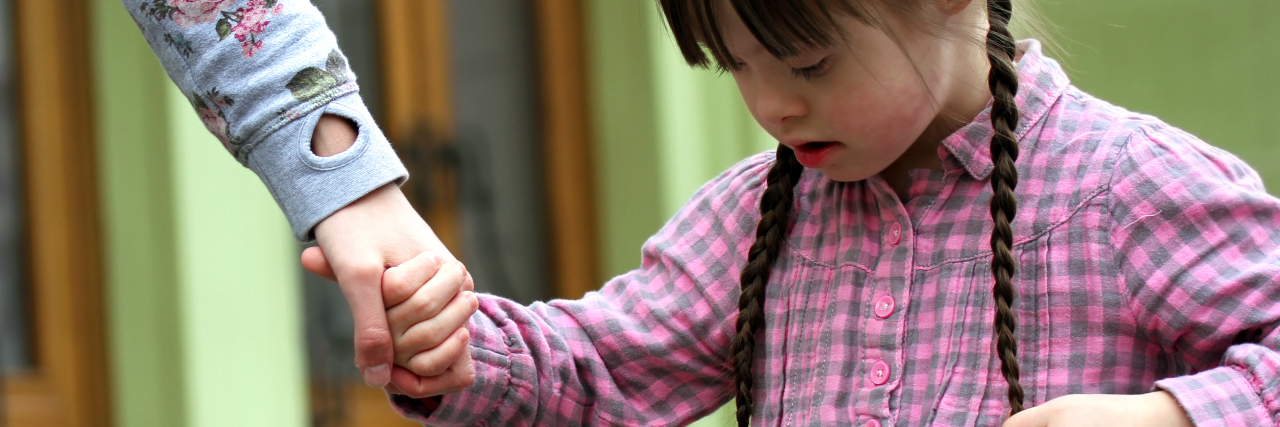 Parenting a Child With Williams Syndrome and Autism Girl holding arms of the mother on a walk .