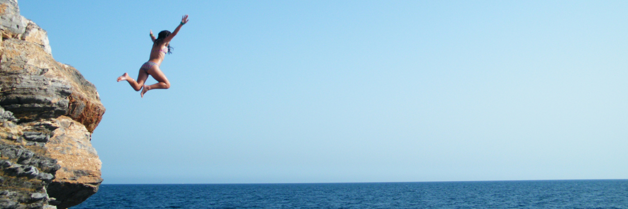 The Accident That Triggered Symptoms of My Genetic Mutation woman jumping off a cliff into the ocean