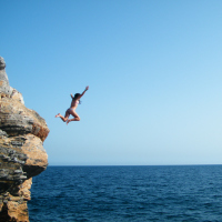 woman jumping off a cliff into the ocean