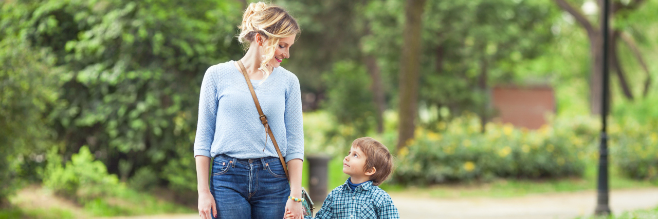 7 Challenges That Only Moms With Chronic Illness Will Understand A young mother and her 5-year-old son walking in a park while holding hands.