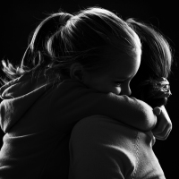 Black and white image of a little girl hugging her mother