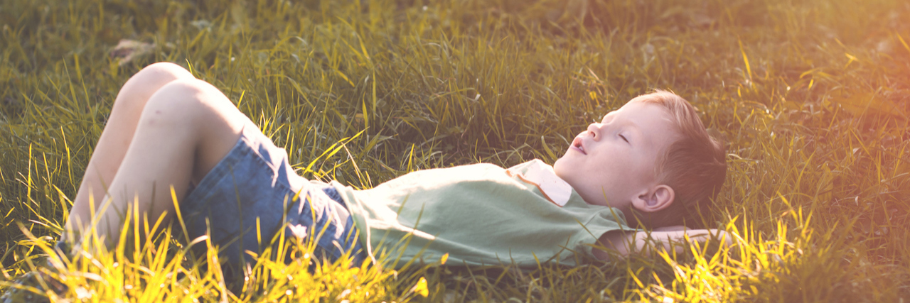 Using Invisibility to Survive in an Abusive Home child sitting in the grass