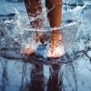 woman's feet splashing in a puddle on a rainy day