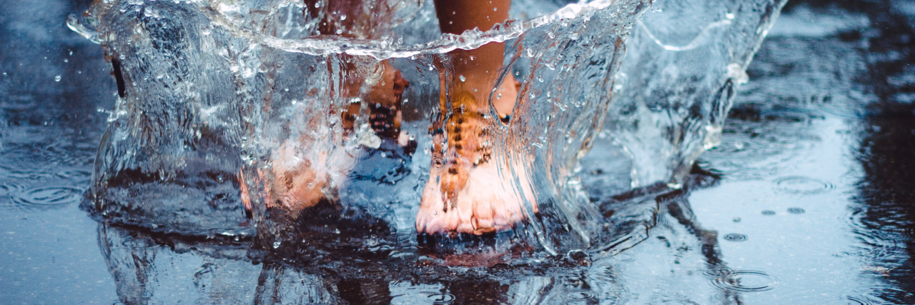 Learning to Dance in the Rain of Chronic Illness woman's feet splashing in a puddle on a rainy day