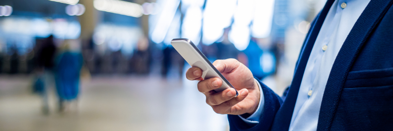 How Social Media Hurts and Motivates Me With Congenital Heart Disease Close up of unrecognizable hipster businessman with smartphone standing on subway station