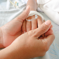 mother holding child's hand who has an iv