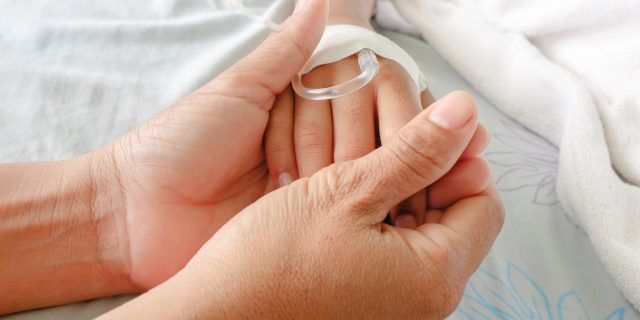 mother holding child's hand who has an iv