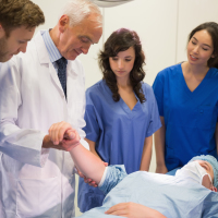 Medical students and professor examining patient.