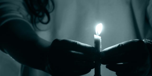 How You and I Can 'Bring Hidradenitis Suppurativa to Light' A woman holding a lit candle in the dark.