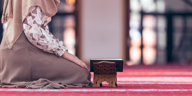 7 Ways to Navigate Ramadan If Your Health Prevents You From Fasting A picture of a Muslim woman kneeling on the ground, reading her Quran.