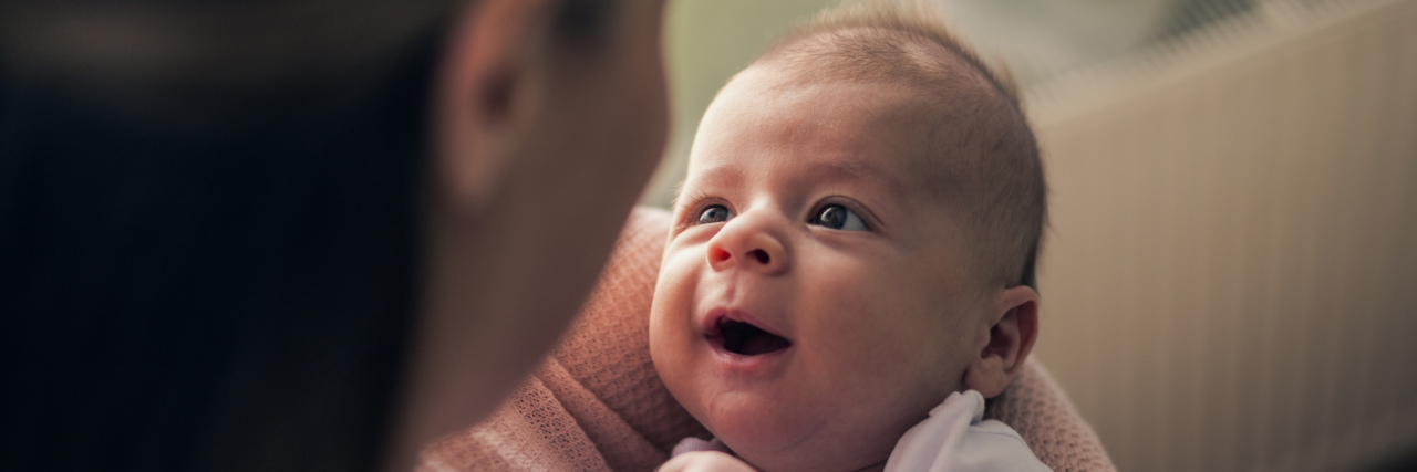 To a New Mum With EDS, From Your Fellow Spoonie A woman holding a new born baby that is looking up at her.