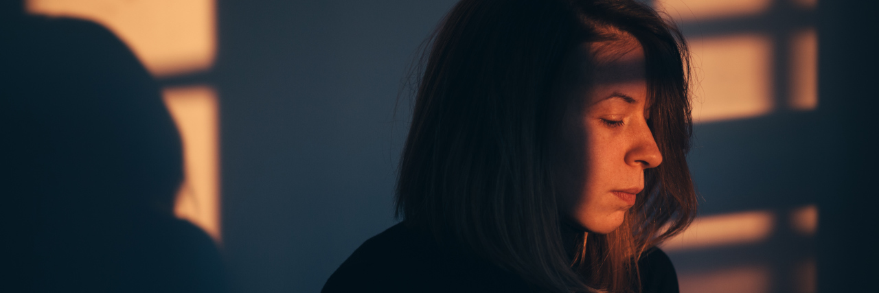 Anxiety and Cerebral Palsy Woman sitting alone and depressed in window light.