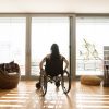 Disabled woman in wheelchair at the window at home.