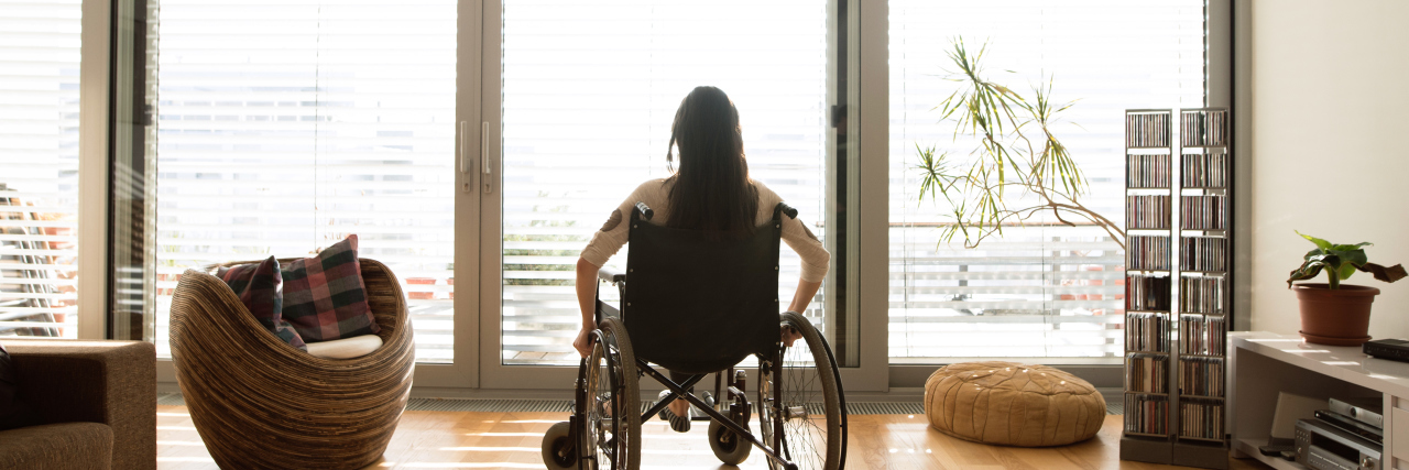 Disabled woman in wheelchair at the window at home.