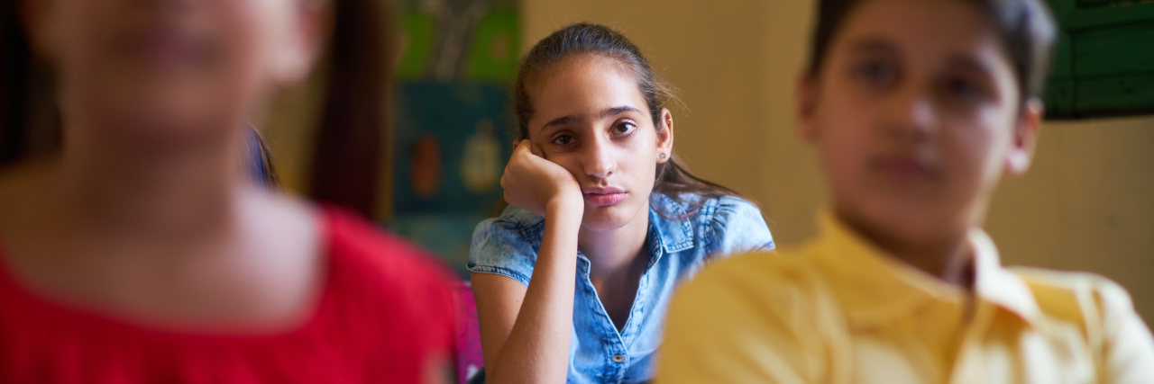 We Need to Have More Conversations About Mental Illness in High School Young people and education. Group of hispanic students in class at school during lesson. Girl with anxiety, bored female student