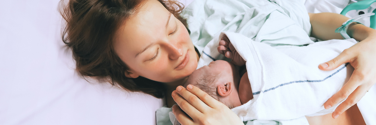 3 Ways to Support a New Parent Struggling With a Postpartum Disorder Mother holding her newborn baby child after labor in a hospital.