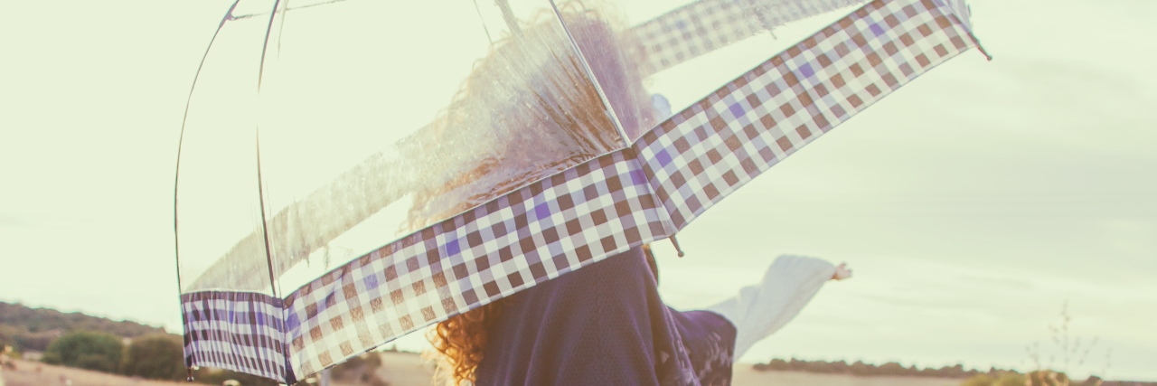 Woman carrying a solar umbrella in a field