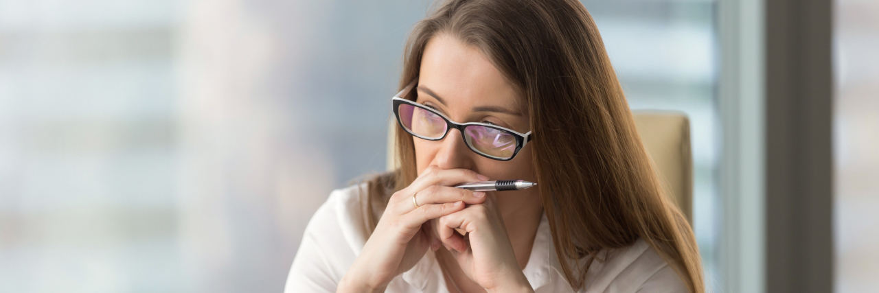 What It's Like to Experience a Hashimoto’s Thyroiditis Flare A woman tired at work, looking at a computer.