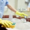 Woman cleaning sink with sponge.