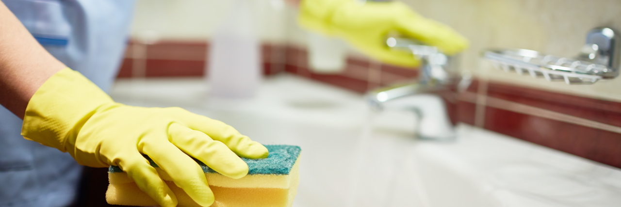 Autism and Blending In Woman cleaning sink with sponge.